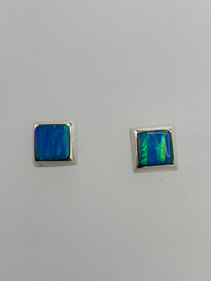 Par de aretes de plata con ópalo de fuego azul, reflejando luz en tonos azul y verde