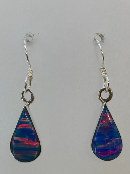 Aretes de ópal de fuego colgando, iluminando los reflejos del color