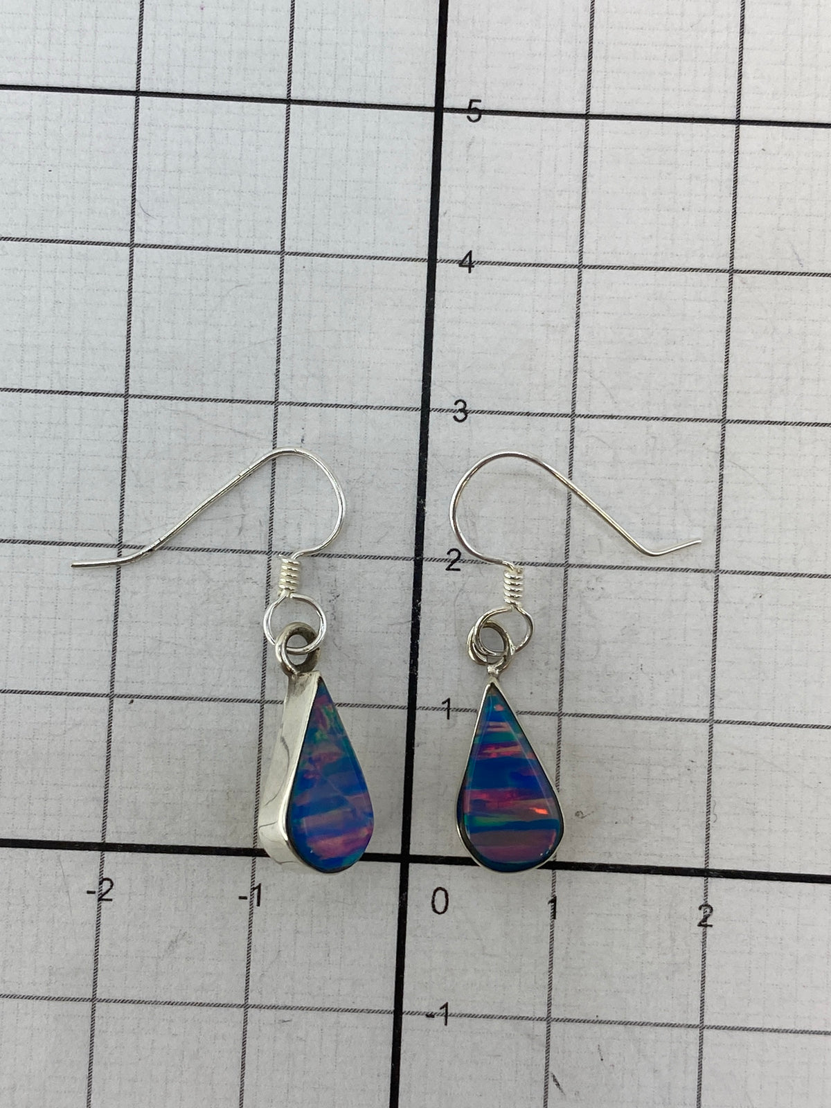 Ópal de fuego multicolor en aretes de plata Taxco sobre fondo blanco