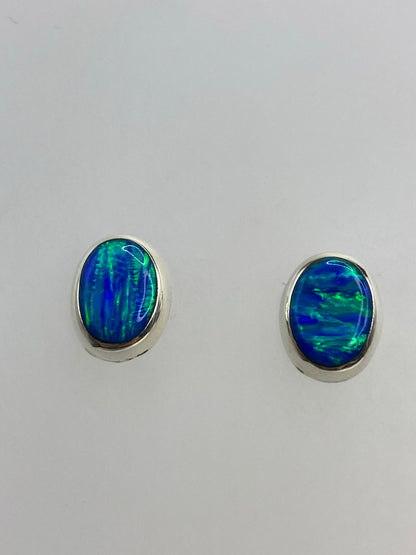 Detalle del ópalo de fuego azul en cada arete, mostrando los reflejos verdes