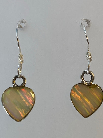 Los dos aretes de ópalo de fuego sobre fondo blanco, con iridiscencia visible