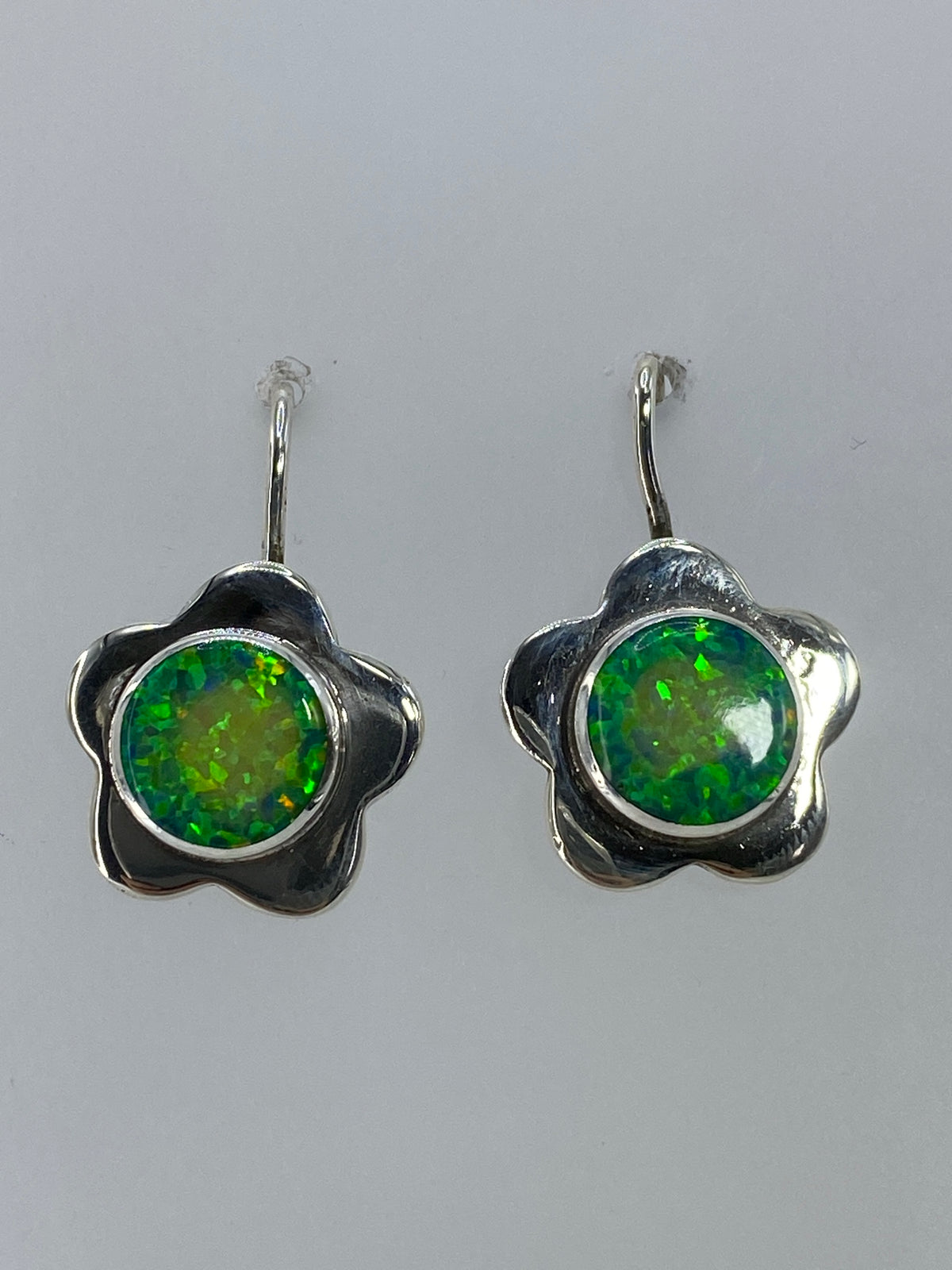 Aretes colgando mostrando el brillo verde limón del ópalo de fuego