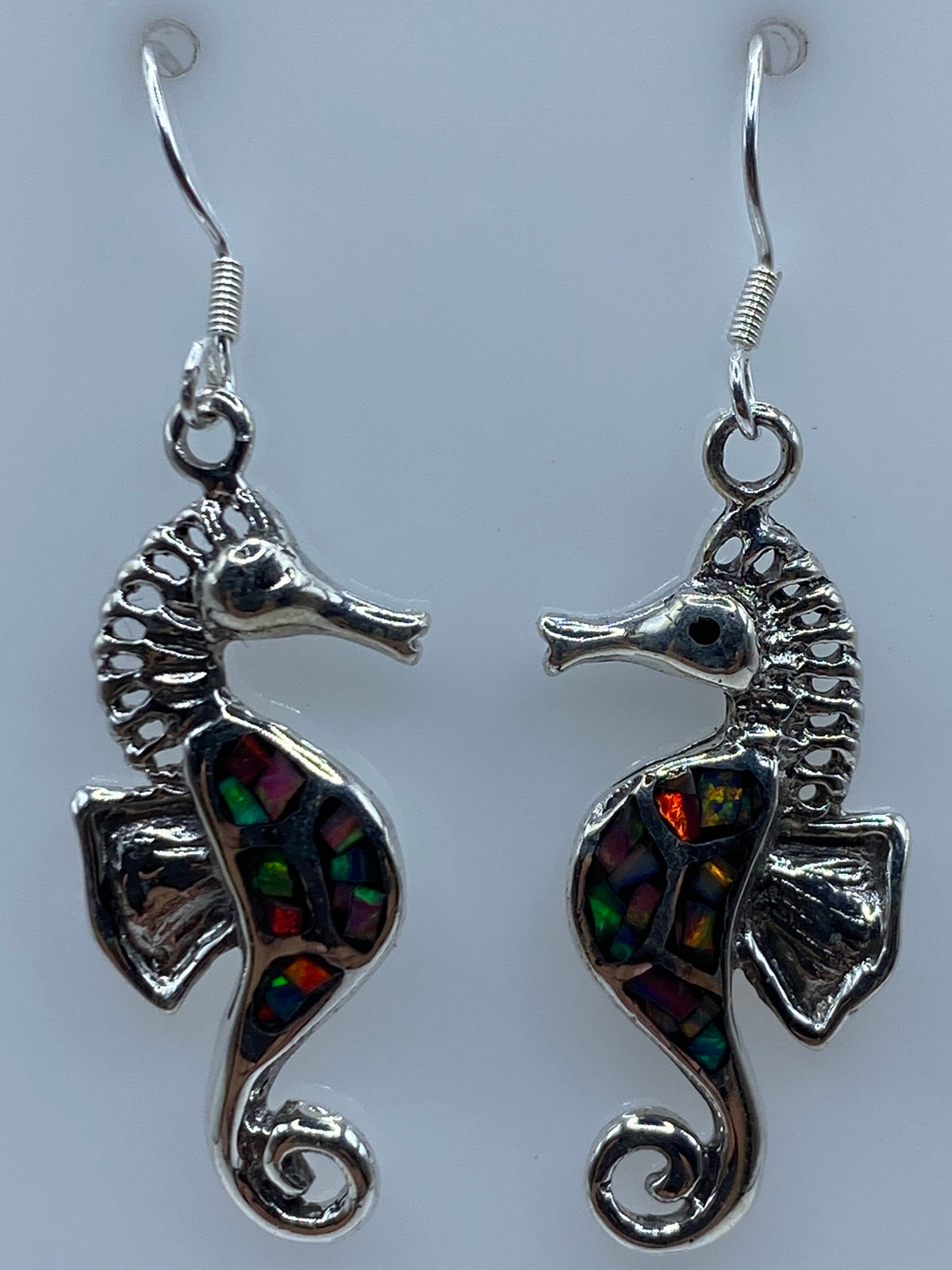 Aretes en la mano mostrando los colores cambiantes del opalo