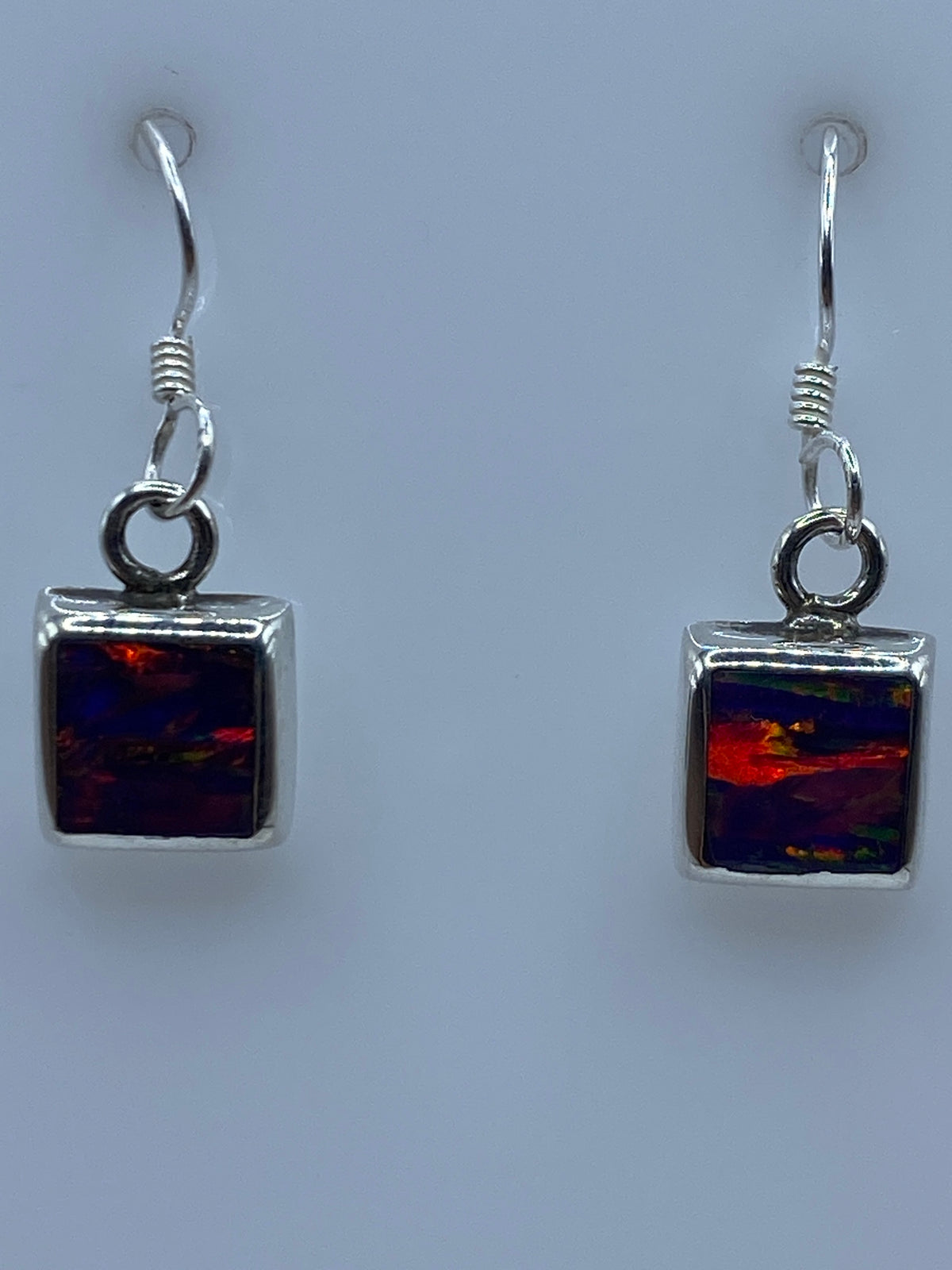 Ópalo de fuego morada en aretes de plata — efecto iridiscente visible bajo luz natural