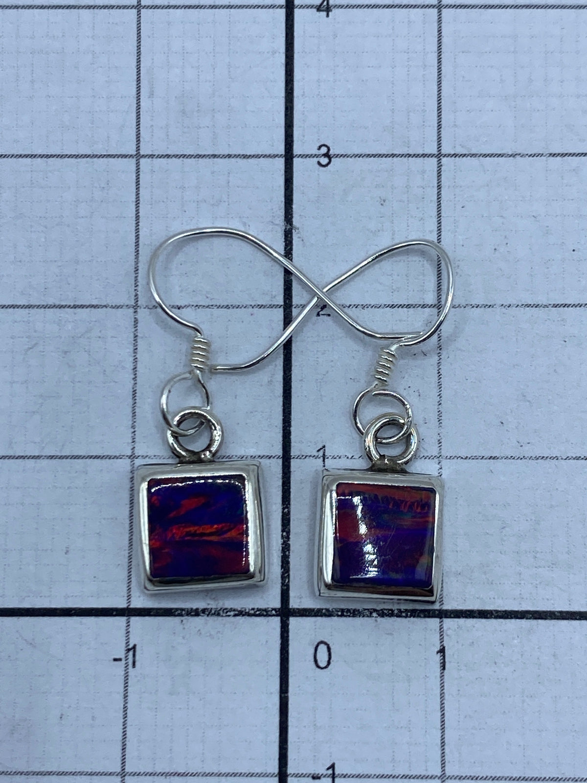 Aretes sobre medidor de pulgadas mostrando largo de 2.4 cm y marca de Quinto 925