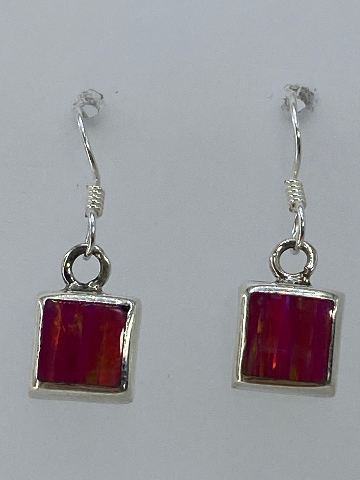 Aretes sobre fondo blanco mostrando el brillo rosa del ópalo de fuego