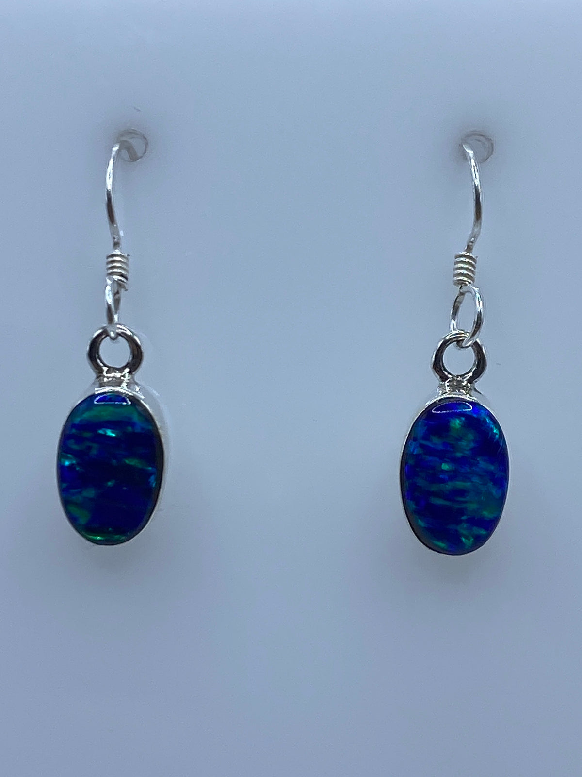 Par de aretes de plata 950 con ópalo de fuego azul, gancho de plata, fotografiados en fondo blanco