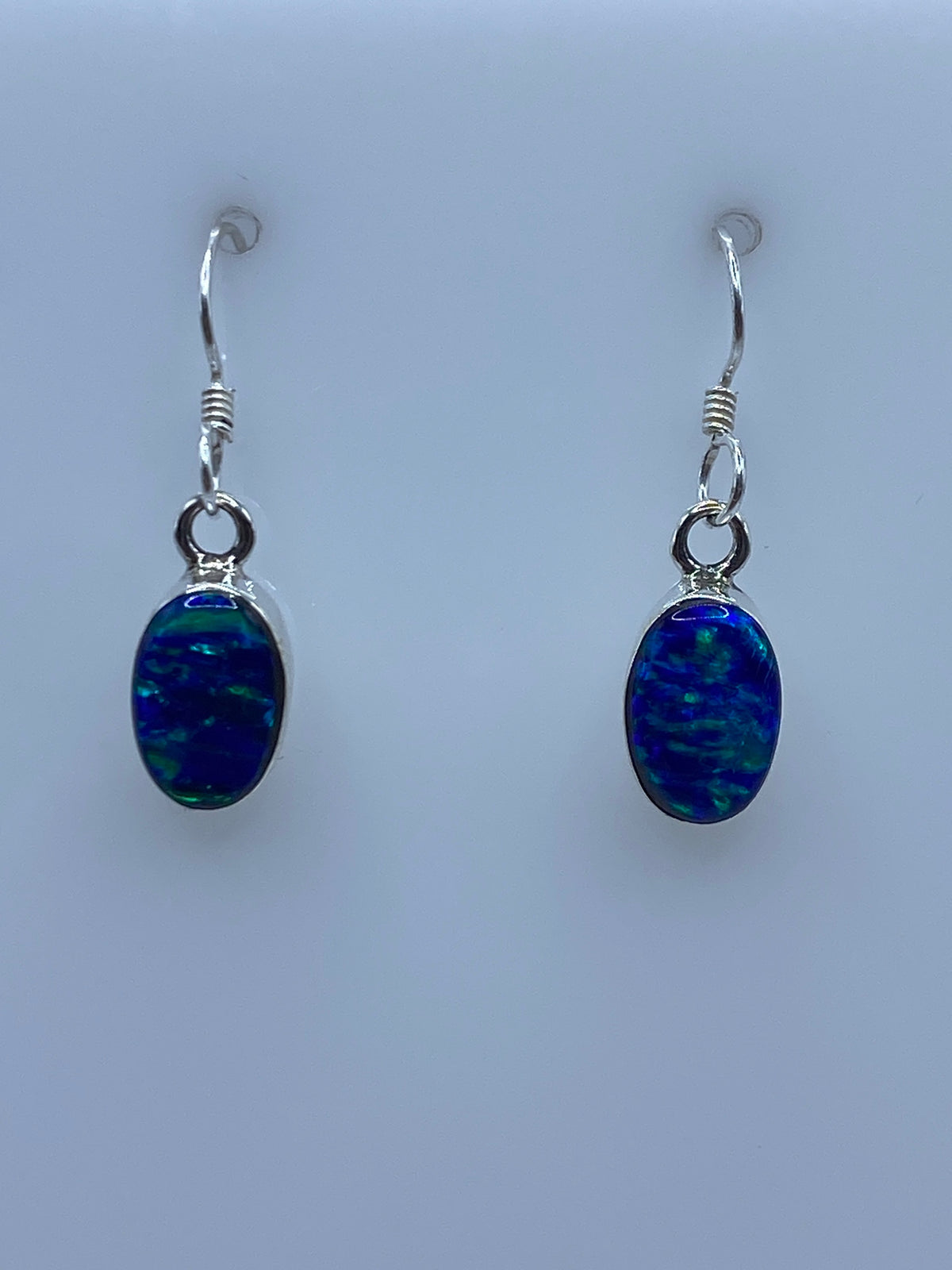 Detalle frontal del ópalo de fuego azul engastado en plata 950, mostrando el juego de luz azul y verde