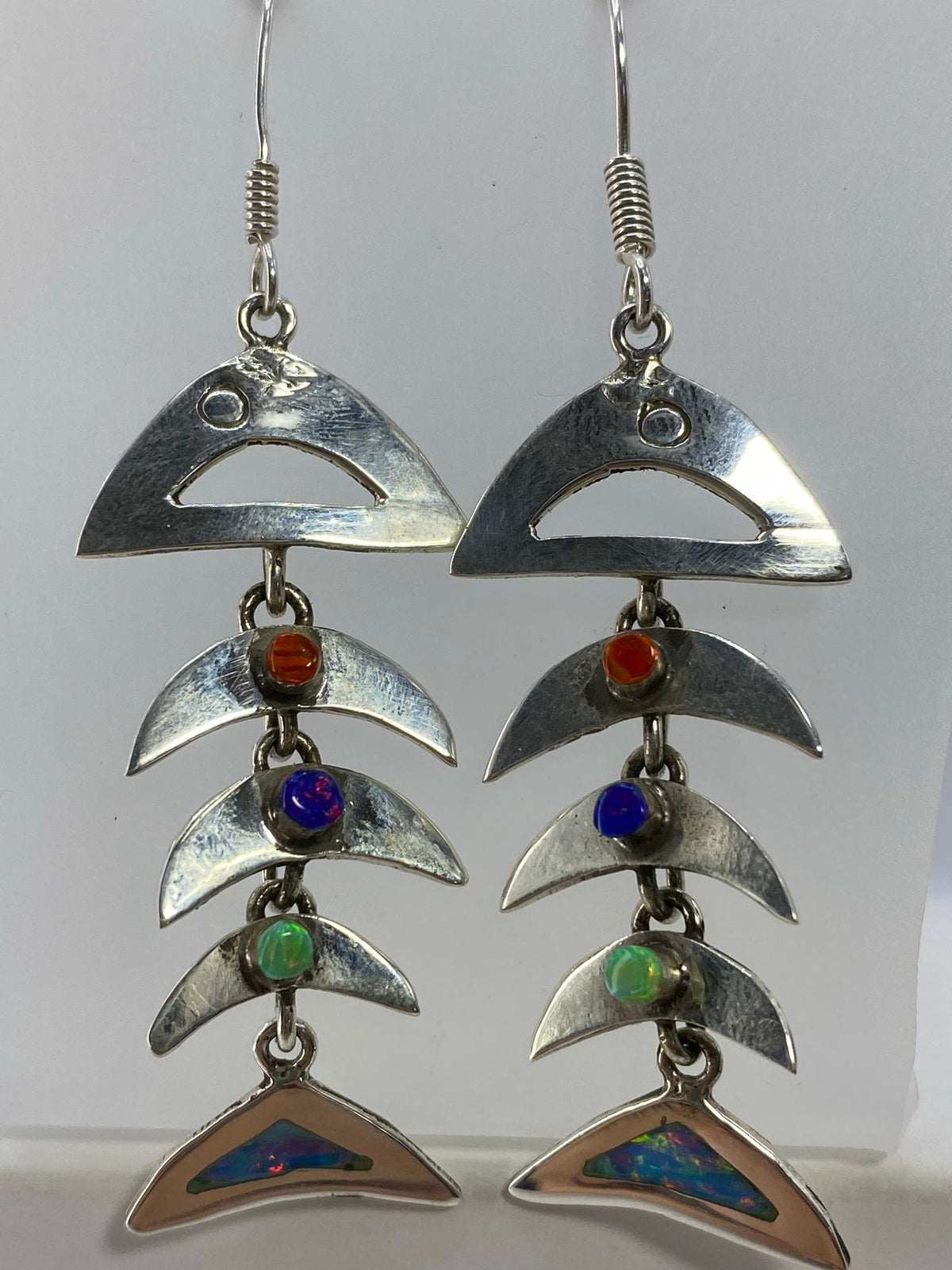Detalle del ópalo de fuego con reflejos azules y verdes en la base de los aretes
