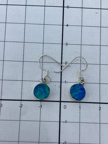 Aretes de plata con ópalo de fuego junto a regla métrica, 2.3 cm de largo
