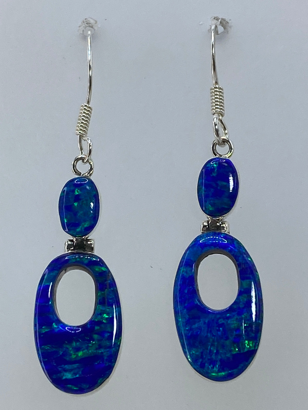 Aretes de plata 950 con ópalo en la mano, luz atravesando la piedra