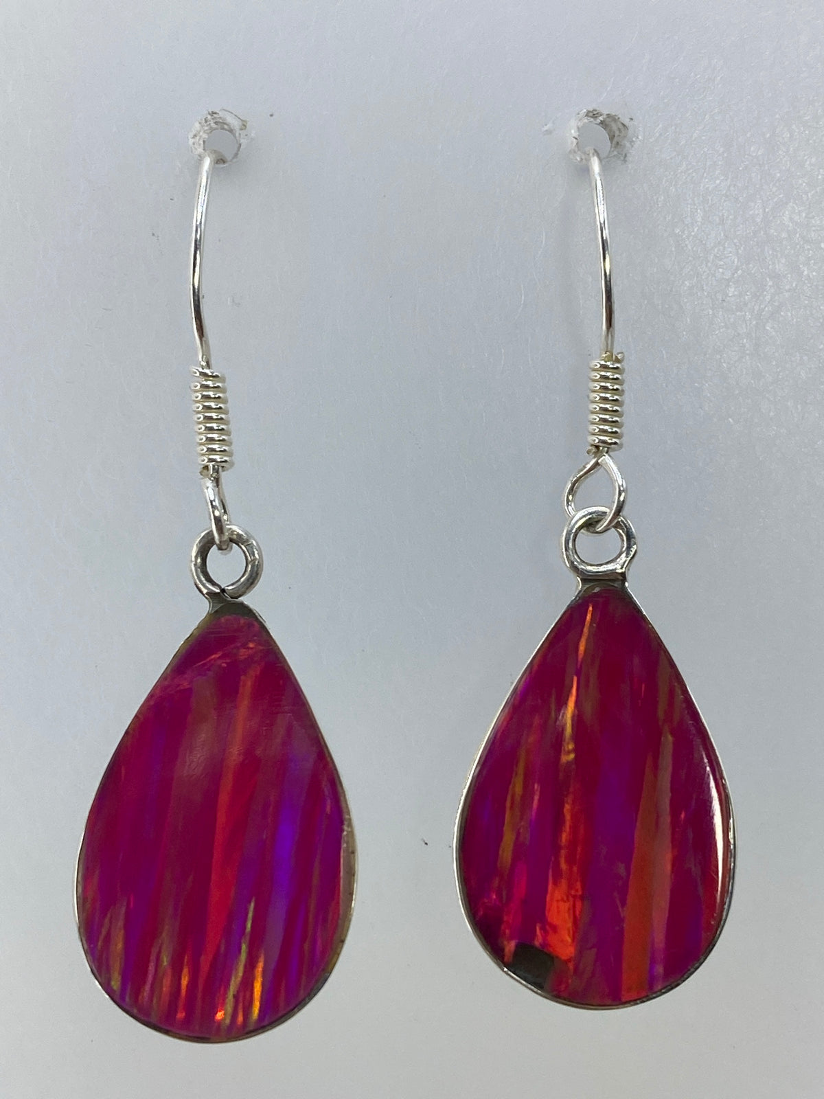 Aretes colgando, mostrando el brillo translúcido y los reflejos del ópalo rosa