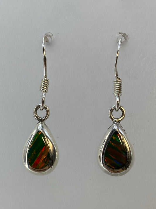 Aretes de plata con ópalo de fuego verde en forma de gota, colgando sobre fondo blanco