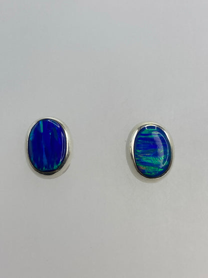 Par de aretes de plata con ópalo de fuego azul engastado, sobre fondo blanco