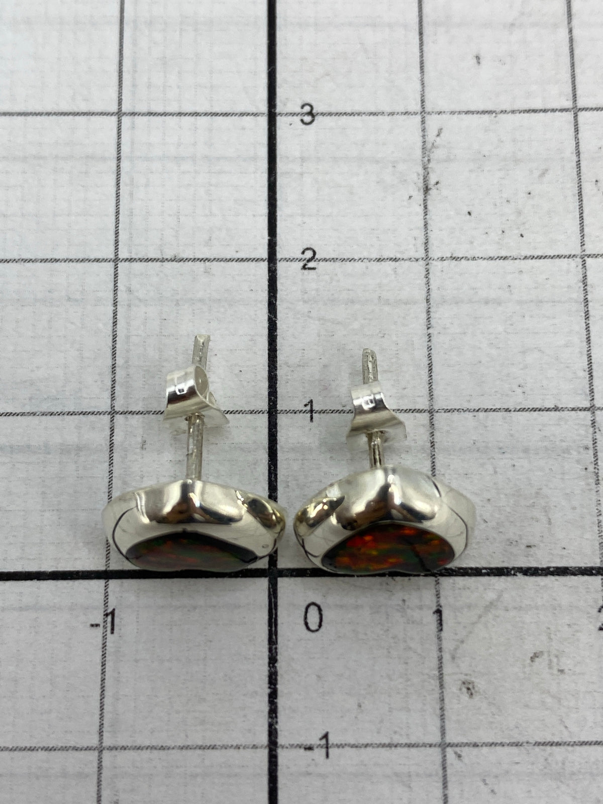 Aretes en mano mostrando el tamaño delicado de 1.4 cm