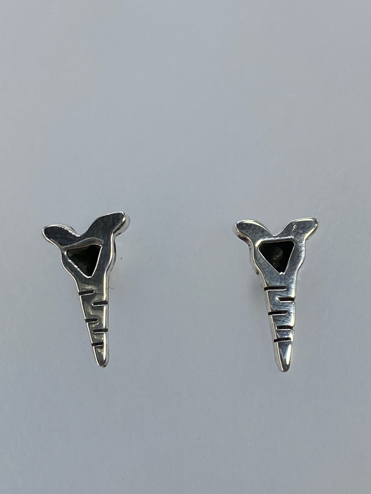 Par de aretes de plata cartoneado con diseño geométrico abstracto, vistos de frente