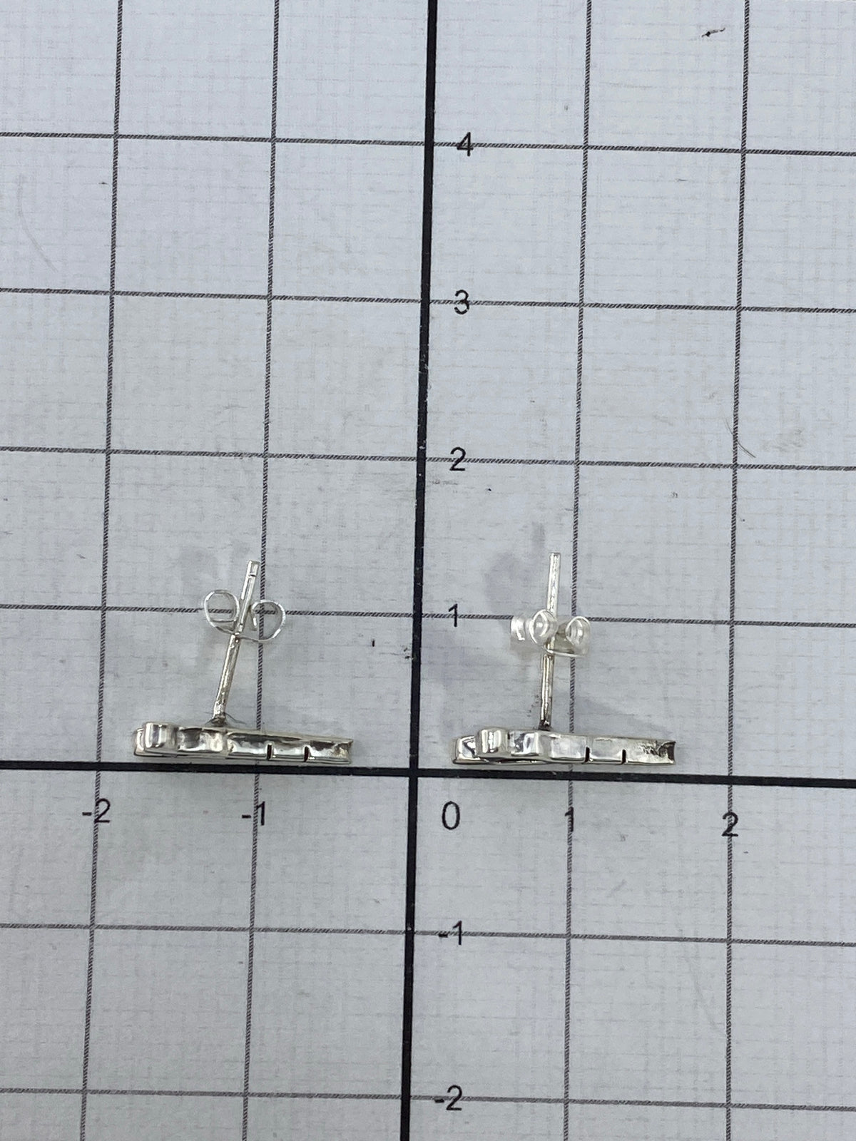 Aretes en mano mostrando el tamaño real de 1.2 cm de largo