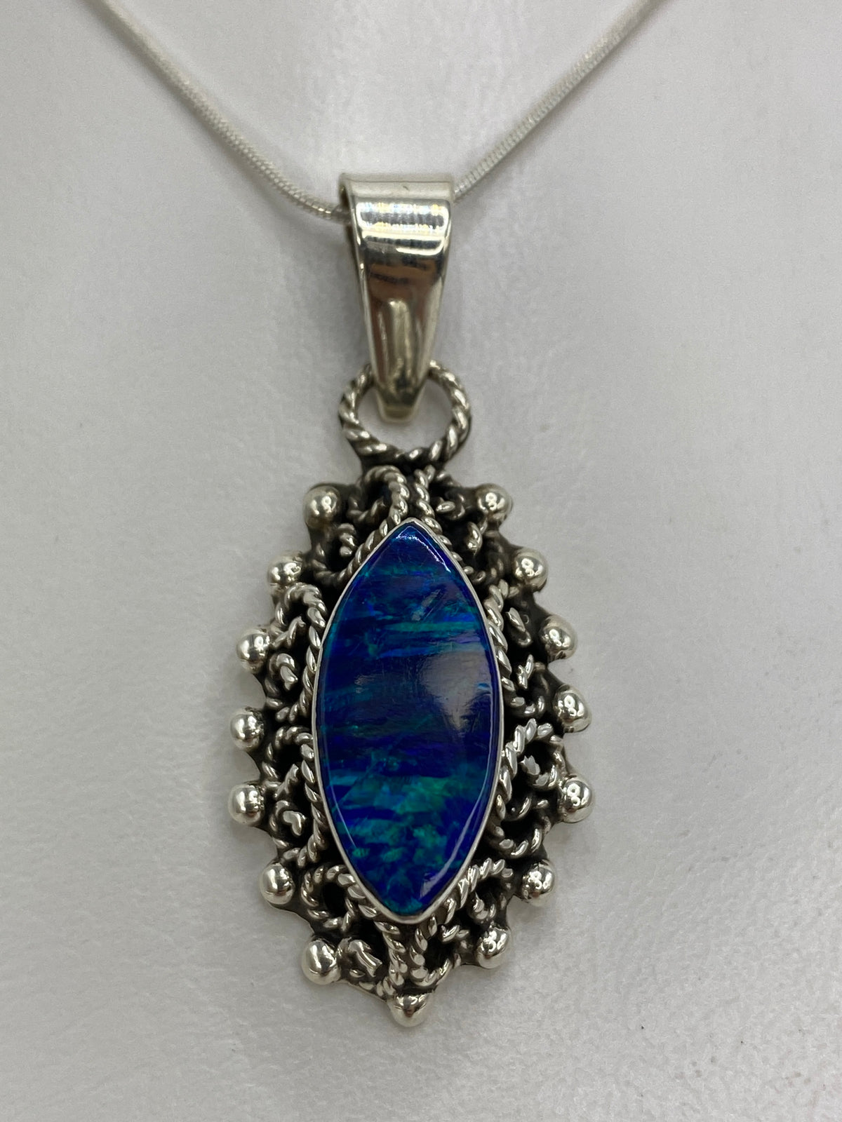 Dije de plata barroco con ópalo de fuego azul iridiscente colgando de cadena