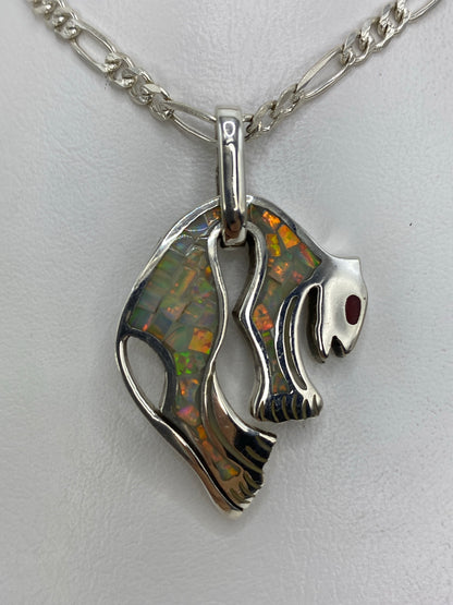 Detalle frontal del dije mostrando el ópalo de fuego con juegos de luz blanca, amarilla y roja incrustado en la calavera