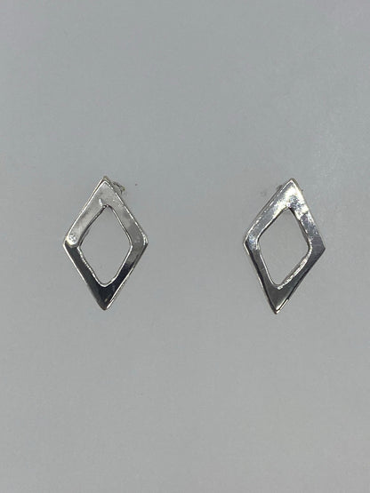 Aretes de plata cartoneado minimalista vistos de frente sobre fondo gris
