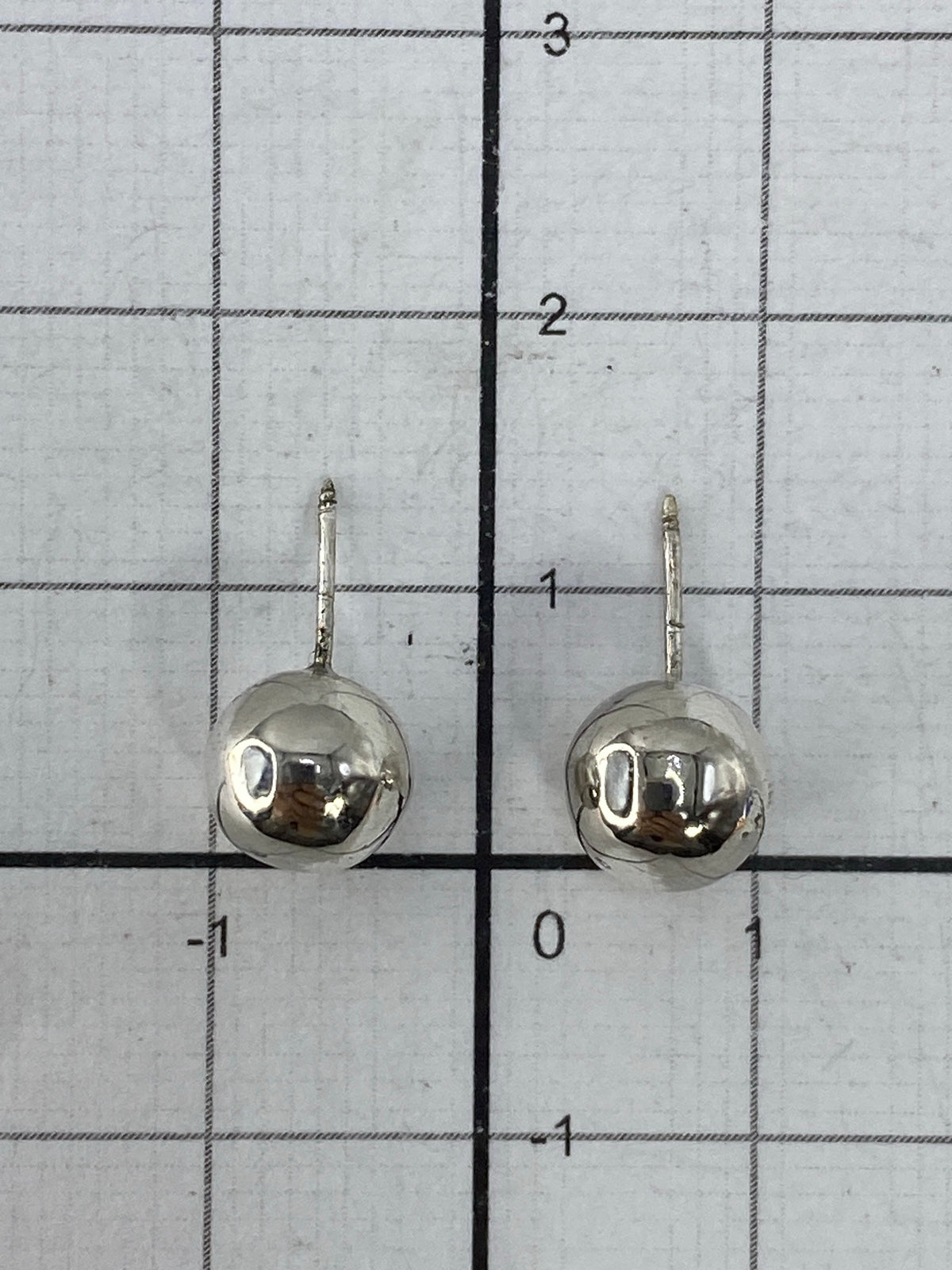 Aretes en la mano mostrando el tamaño minimalista y el peso ligero