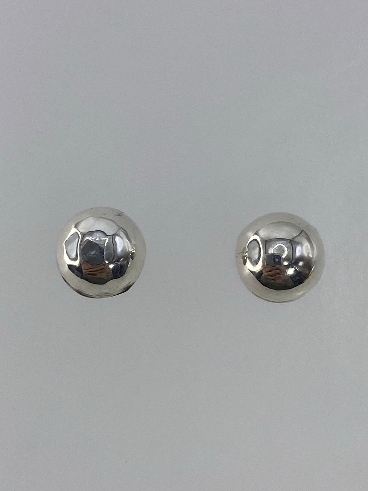 Aretes de plata cartoneado minimalista, par, sobre fondo gris