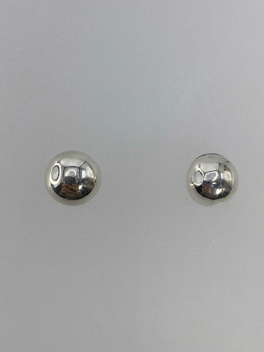 Par de aretes de plata cartoneado, esferas brillantes sobre fondo neutro