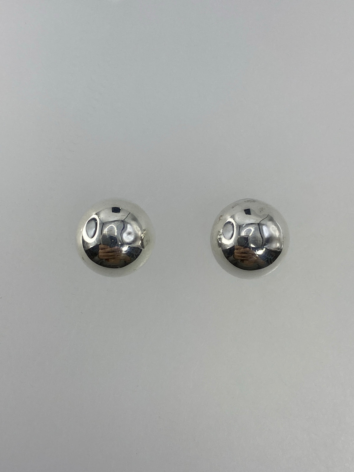 Vista frontal de los aretes de plata con cierre tipo mariposa