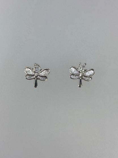 Detalle frontal de los aretes libélula mostrando las alas texturadas en cartoneado
