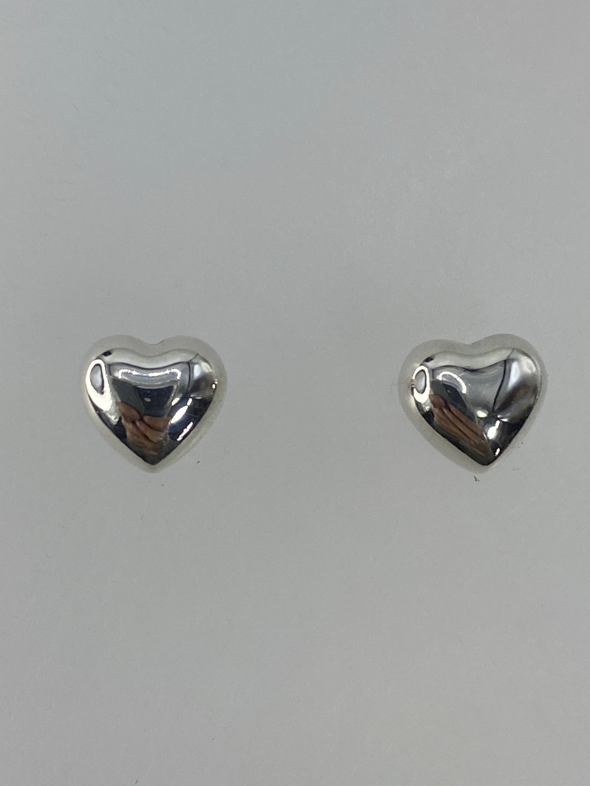 Par de aretes de plata cartoneada, bola pulida, sobre fondo gris