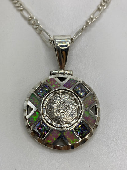Dije circular de plata 950 con Ópalo de Fuego rosa en el centro, rodeado de granulado y triángulos negros