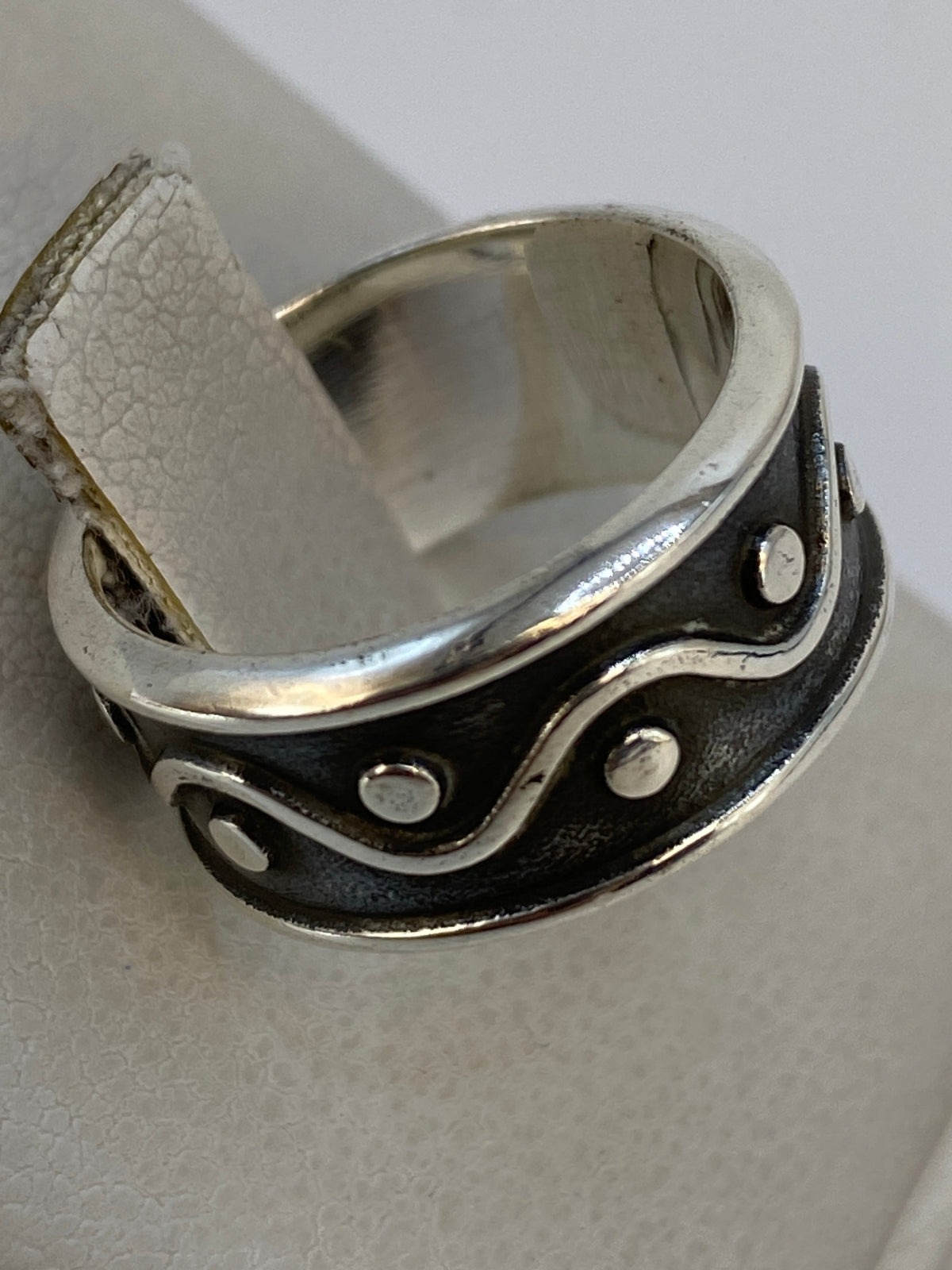 Anillo en la mano mostrando el acabado pulido y contraste de luz