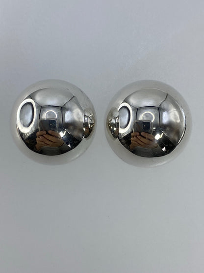Par de aretes de plata cartoneado con forma esférica brillante en mano
