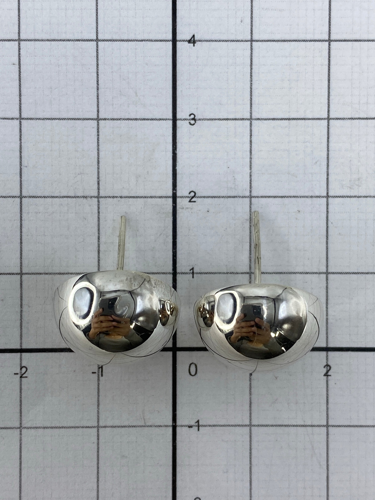 Aretes de plata de Taxco sobre fondo blanco mostrando simetría