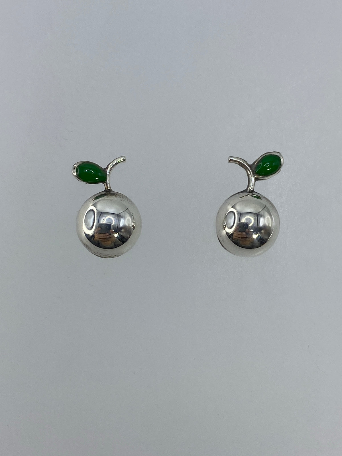 Par de aretes de plata 925 en cartoneado visto de frente mostrando la forma redonda perfecta