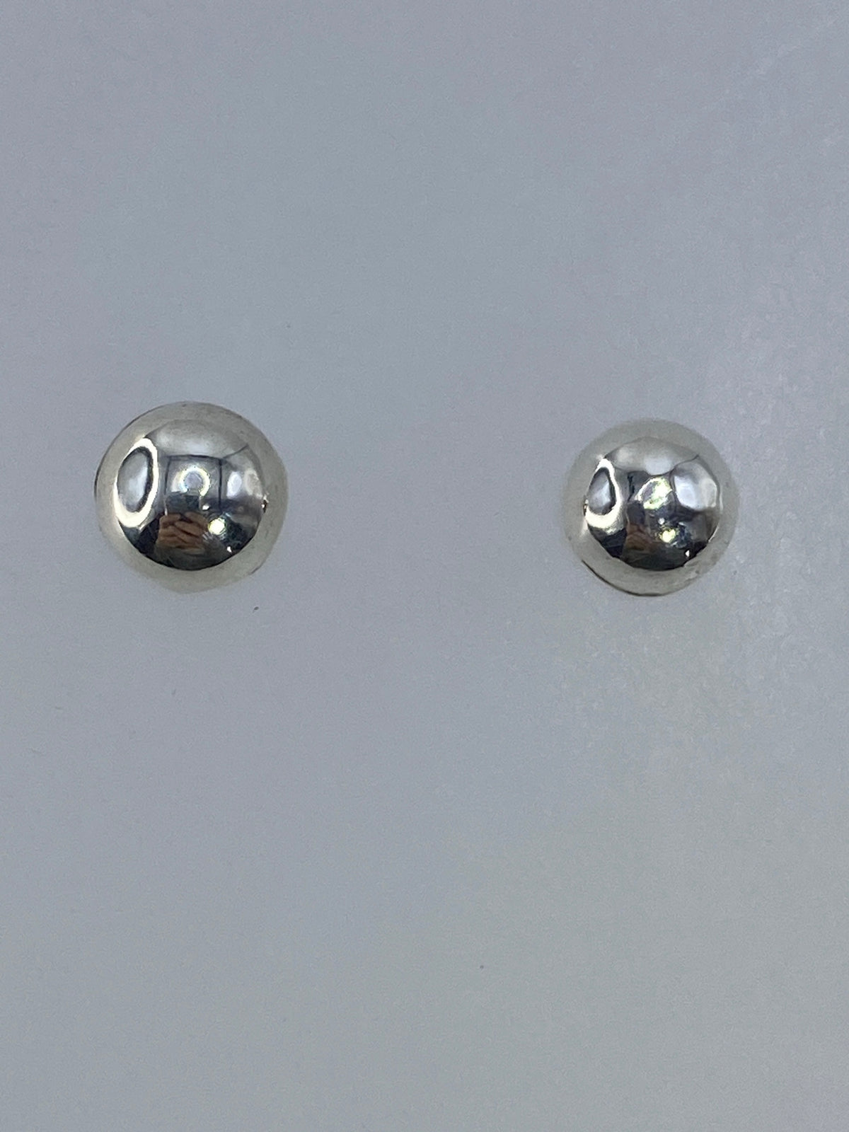 Par de aretes de plata 925 en cartoneado, esfera pulida brillante, en mano