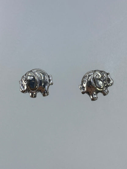 Aretes de plata elefante en cartoneado, vistos de frente sobre fondo gris