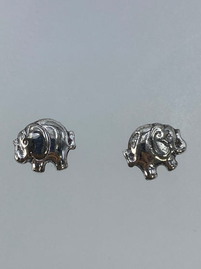 Aretes elefante en mano, mostrando escala pequeña (1.1 cm)