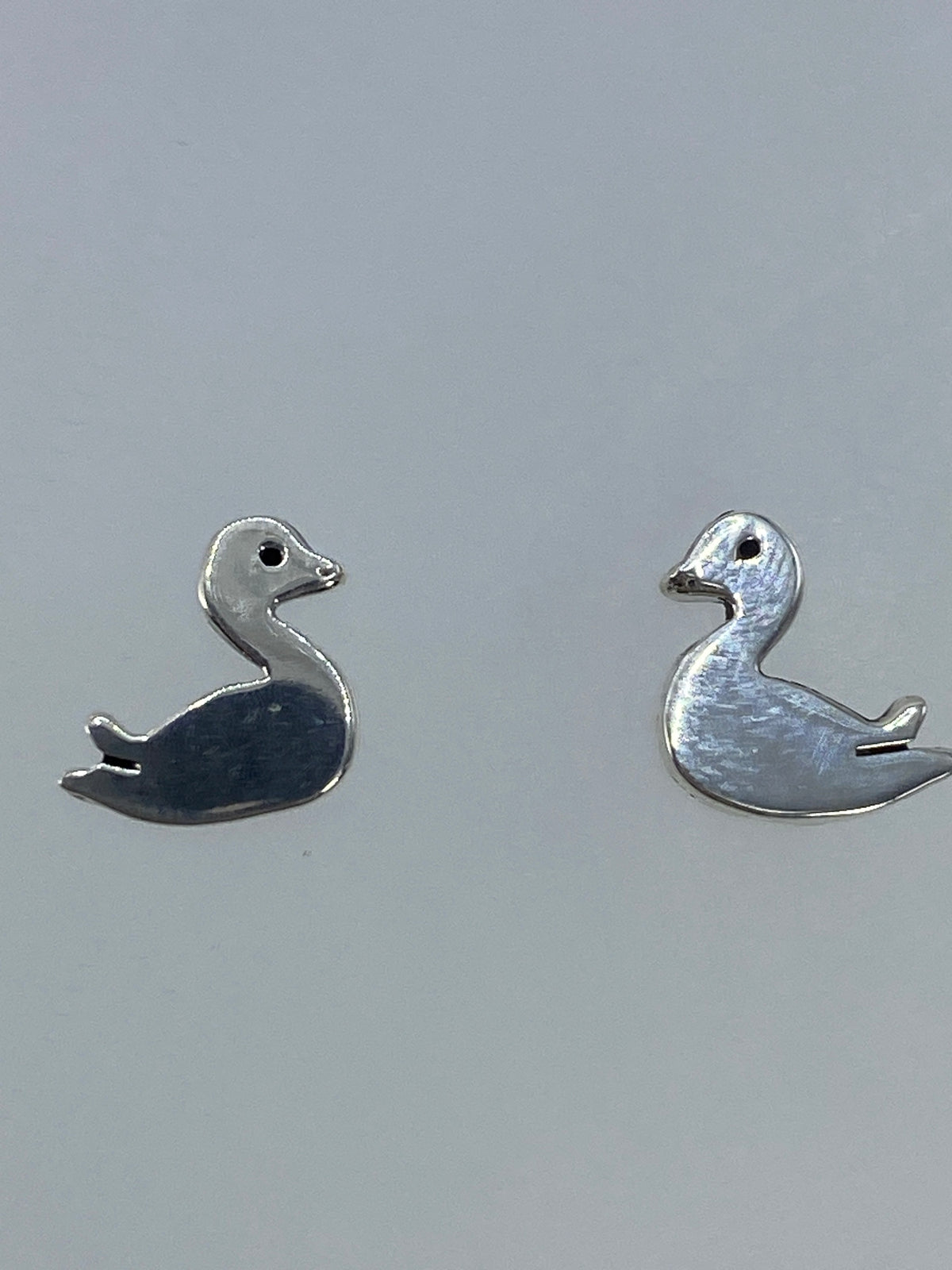 Detalle lateral de los aretes de pato en plata cartoneada