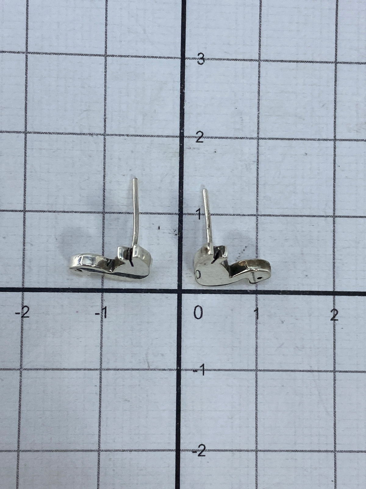 Aretes en la mano mostrando su tamaño diminuto de 1.3 cm