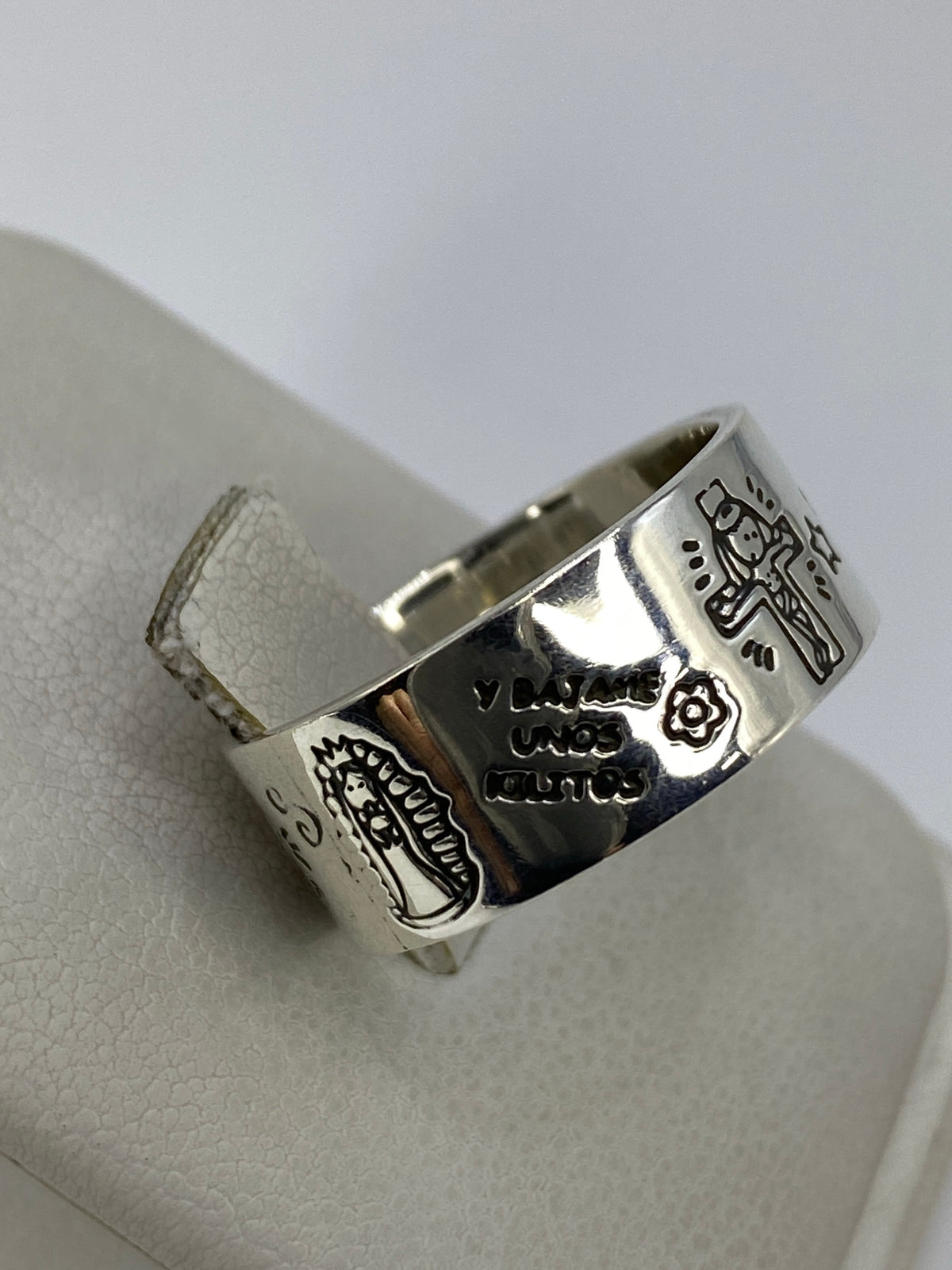 Anillo prehispánico sobre fondo azul, luz natural iluminando los relieves