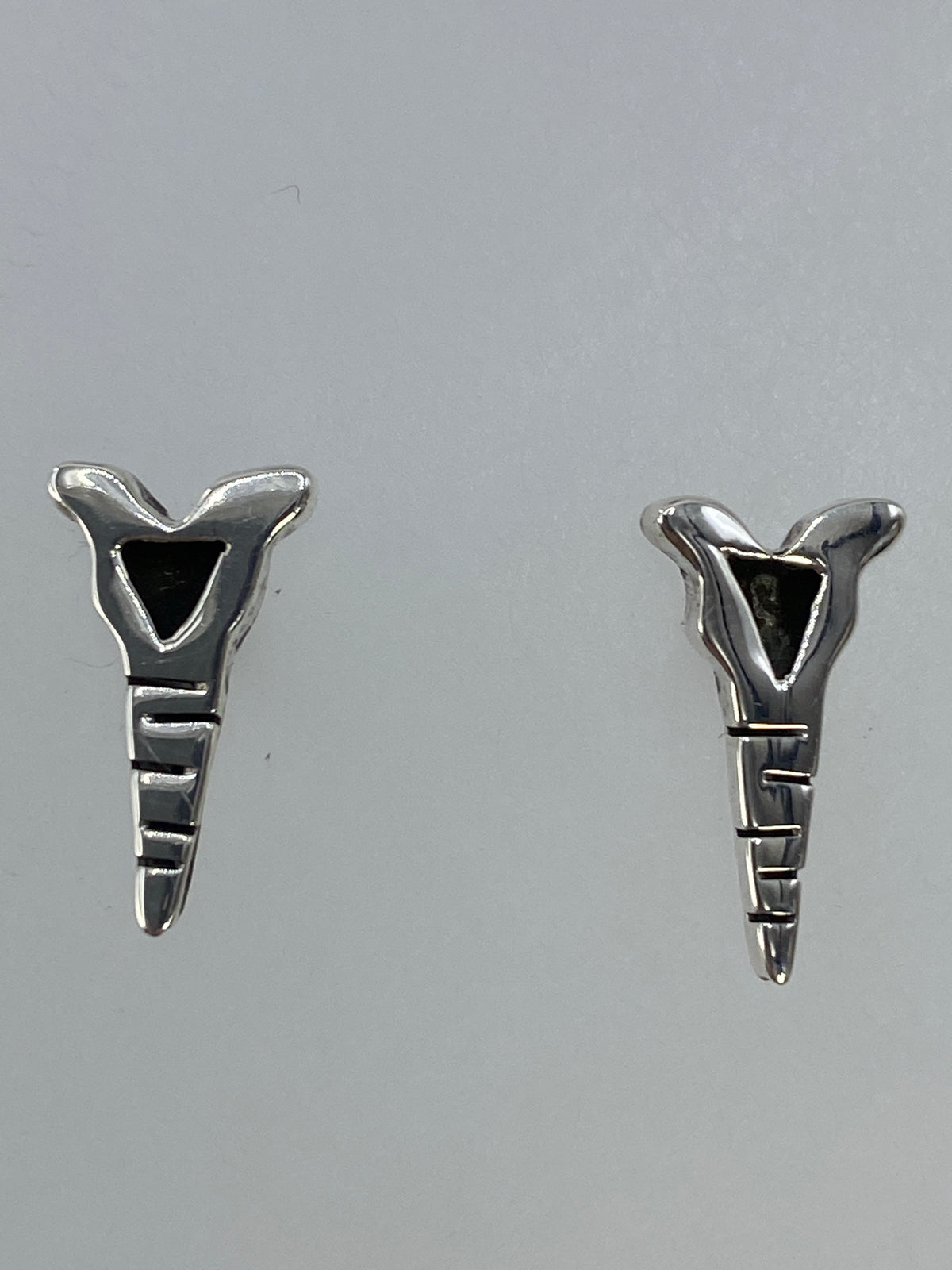 Aretes sobre fondo gris mostrando el Quinto 925 y el acabado pulido