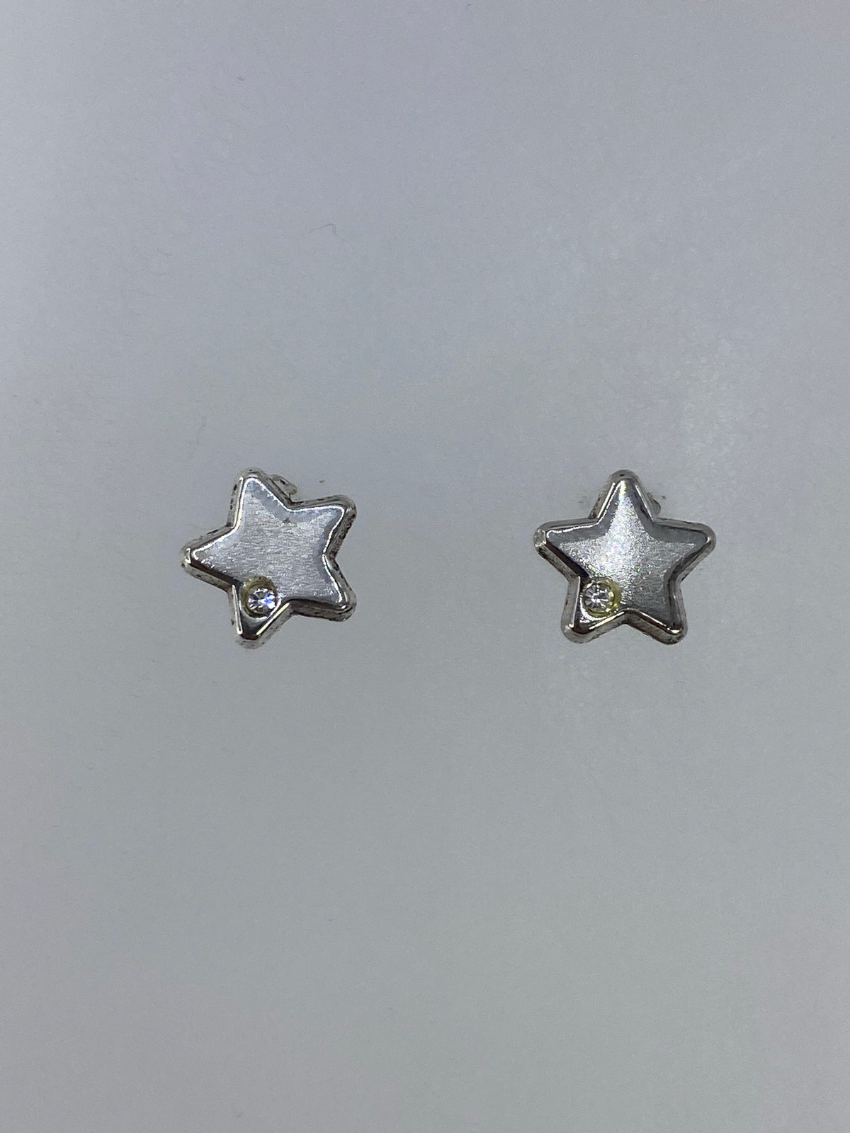 Par de aretes de plata en forma de estrella, cartoneado de Taxco, sobre fondo gris