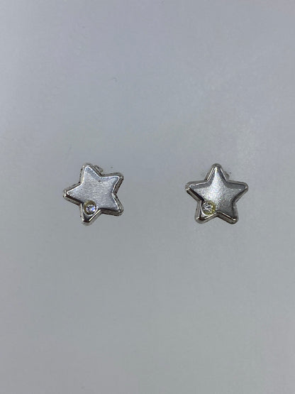 Par de aretes de plata en forma de estrella, cartoneado de Taxco, sobre fondo gris