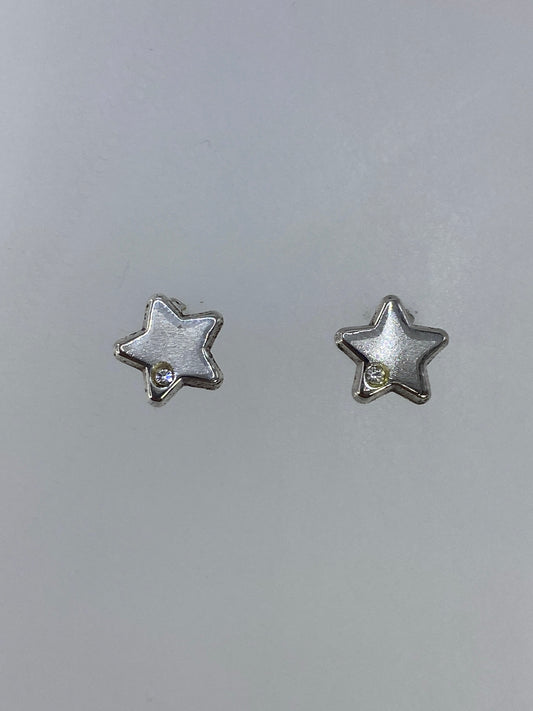 Par de aretes de plata en forma de estrella, cartoneado de Taxco, sobre fondo gris