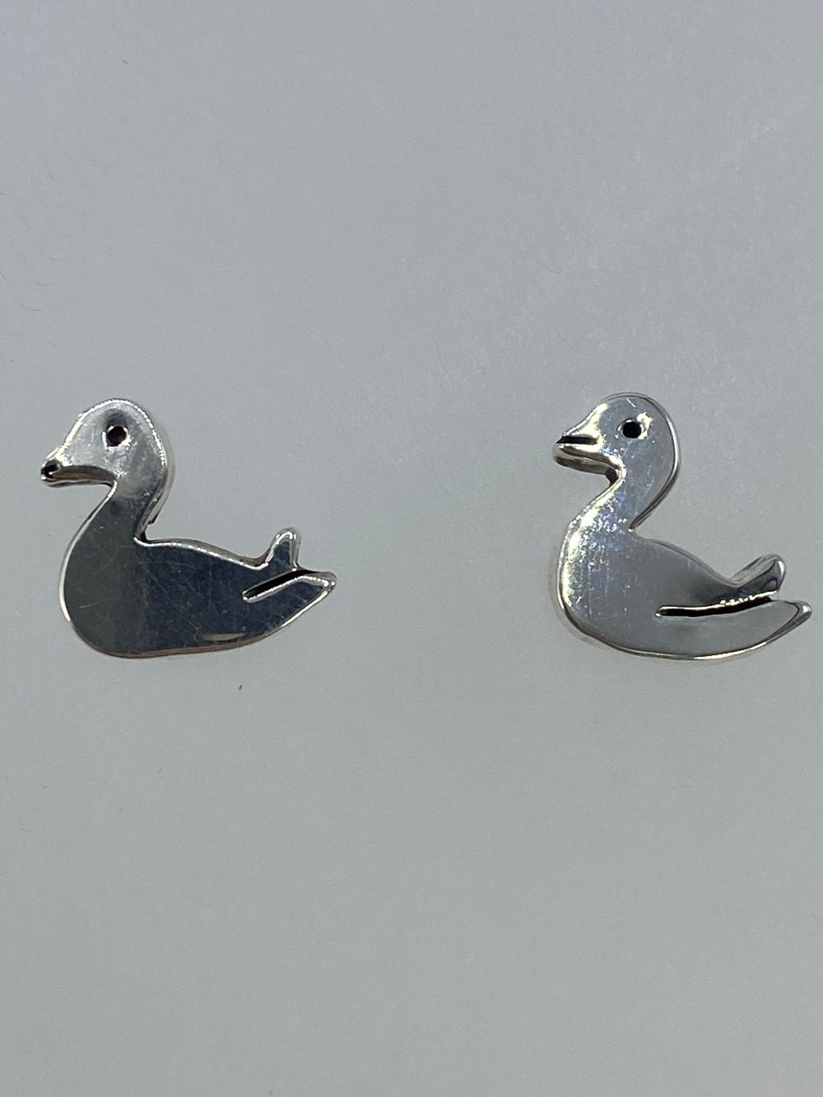 Aretes sobre fondo gris claro mostrando el tamaño real (1 cm)