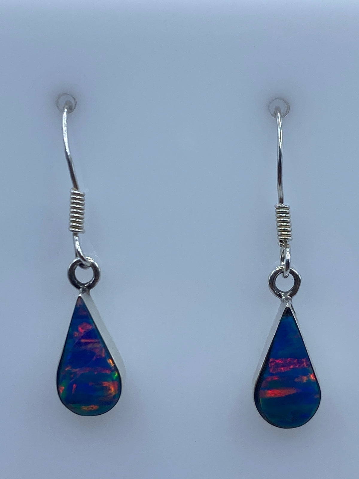 Aretes de plata con opalo de fuego azul, par completo sobre fondo blanco