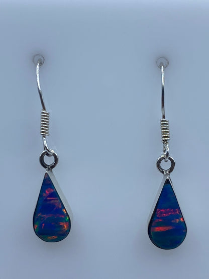 Aretes de plata con opalo de fuego azul, par completo sobre fondo blanco