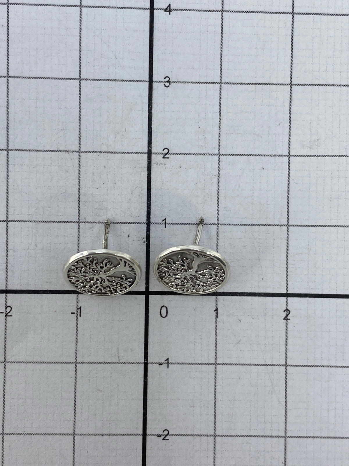 Aretes studs de plata sobre fondo blanco mostrando tamaño minimalista de 1 cm