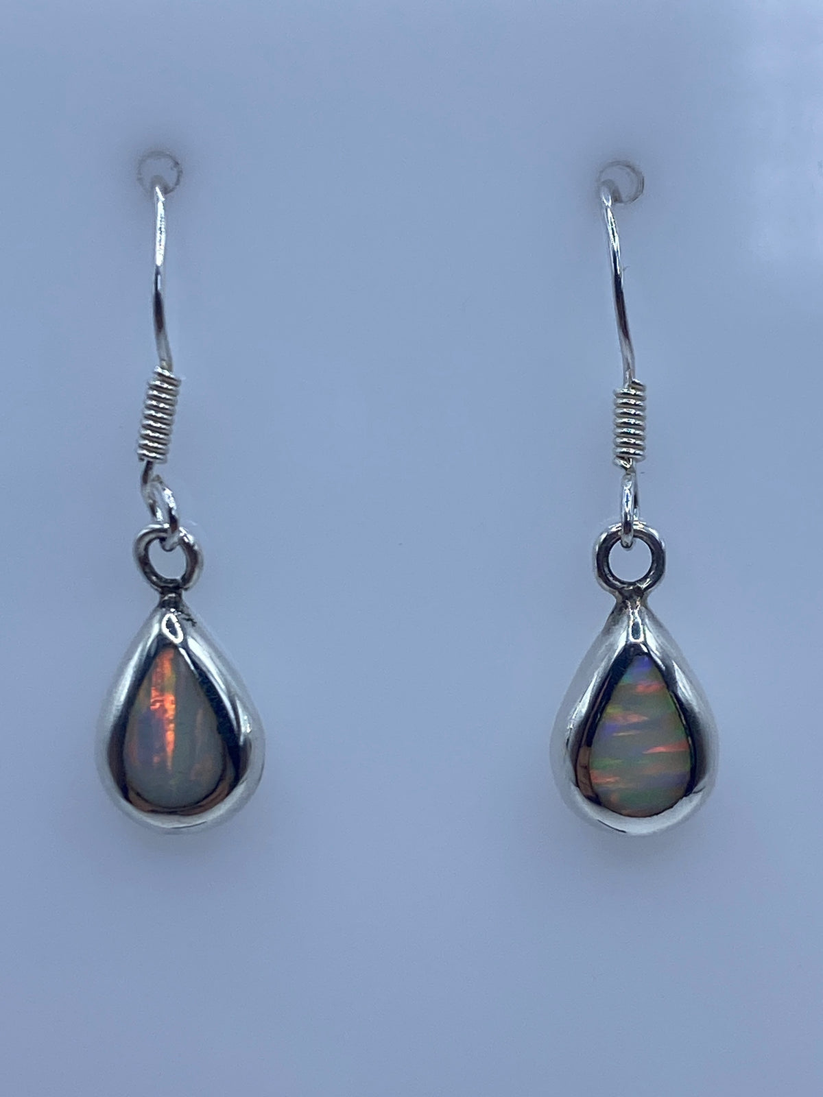Aretes de ópalo de fuego mostrando el juego de colores a la luz